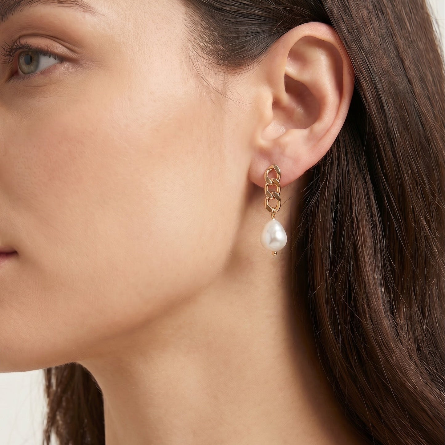 Close-up of a woman wearing pearl earrings with a neutral background